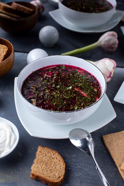 borsh red vegetable soup with bread and sour cream on grey desk