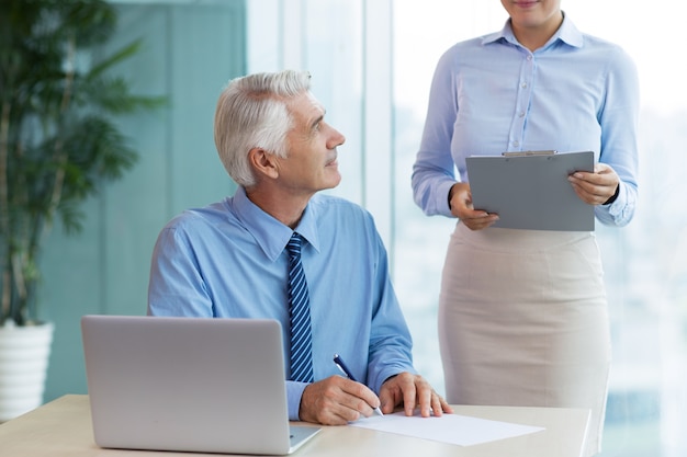 Boss Signing Document and Talking to Secretary