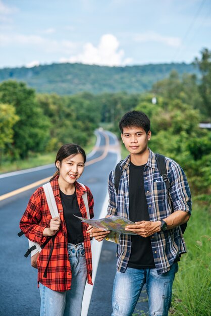 男性と女性の両方の観光客が道路上の地図を見に立っています。