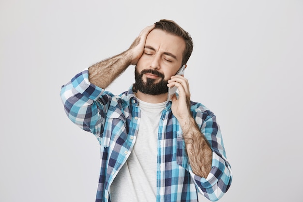 Обеспокоенный и расстроенный мужчина слышит плохие новости во время разговора по телефону