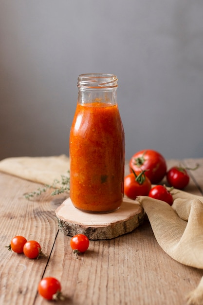 Foto gratuita bottiglia di borscht e pomodori