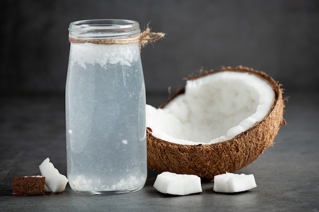 Foto gratuita bottiglia di acqua di cocco messa su sfondo scuro