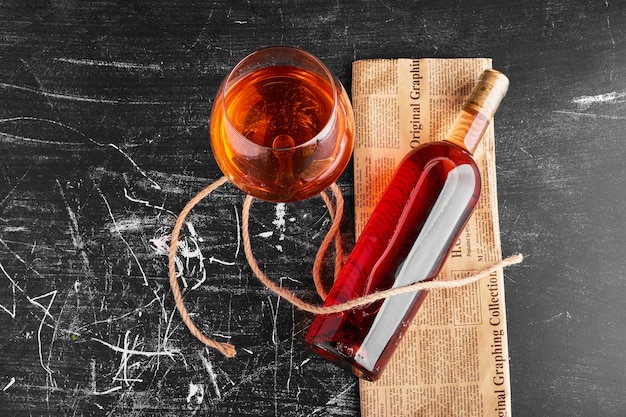 A bottle and glass of rose wine on a vintage newspaper. 