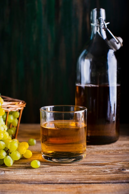 Бутылка и стакан на столе с соком свежего винограда