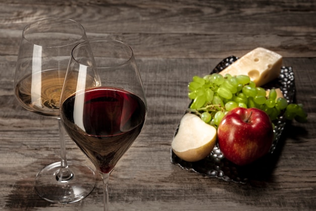 Бутылка и бокалы красного и белого вина с фруктами