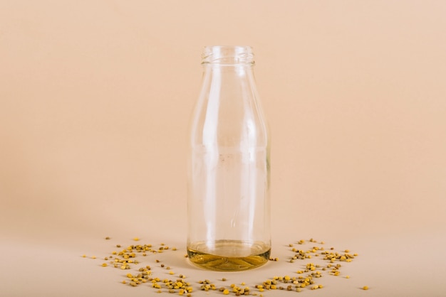 Bottle of honey with bee pollen on peach colored background