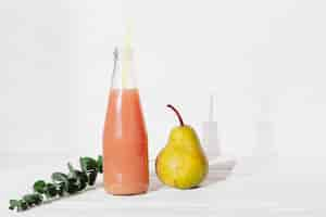 Free photo bottle of juice with pear and leaves