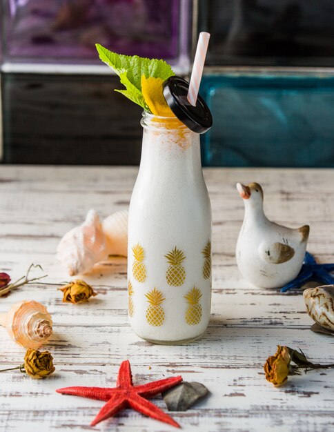 A bottle of milky shake with sea shells.