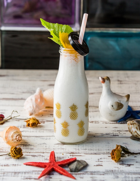 Бутылка молочного коктейля с морскими раковинами.