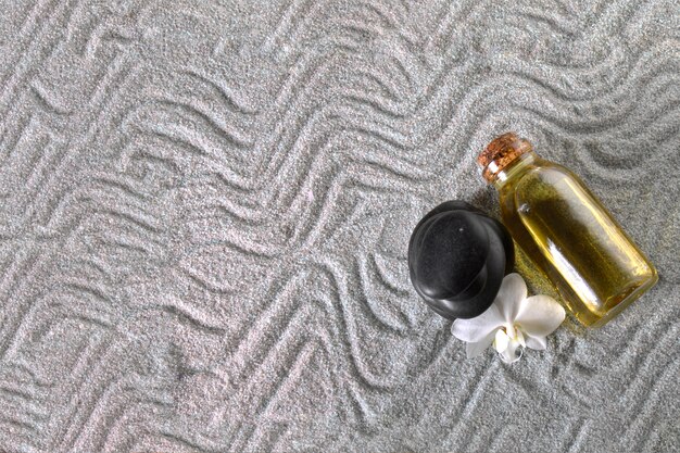 Bottle of oil and black stone on towel