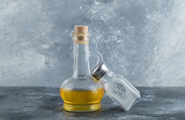 Free photo bottle of oil and salt on grey background.