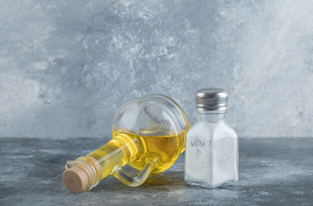 Бутылка масла и соли на сером фоне