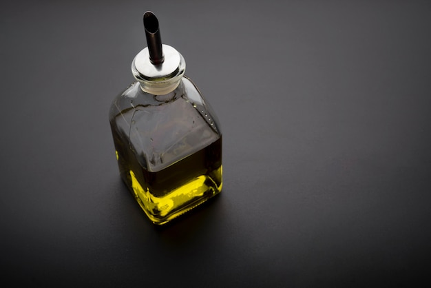 Foto gratuita bottiglia di olio d'oliva su sfondo scuro