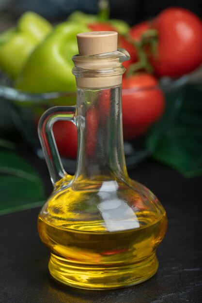 Bottle of olive oil in front of fresh vegetables. 
