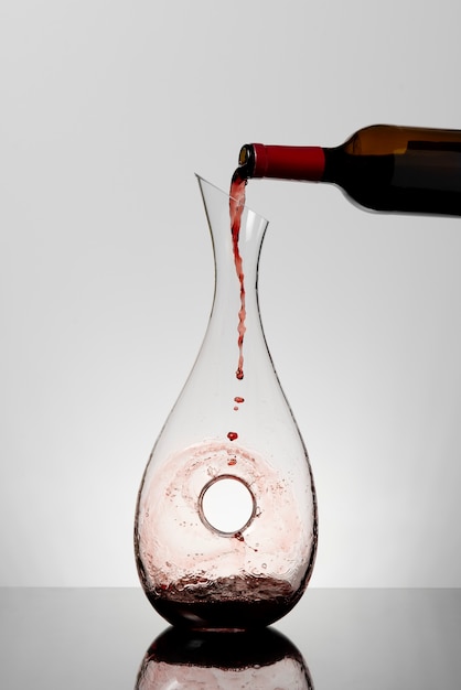 Bottle pouring red wine into carafe