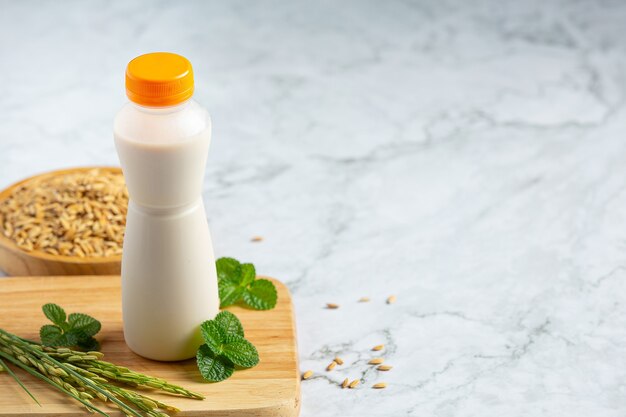 Bottle of rice milk with rice plant and rice seed put on white marble floor