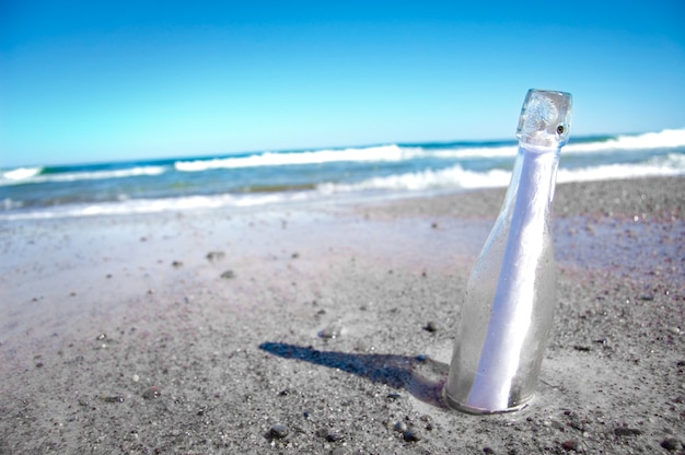 Bottle in the sand with a pape inside