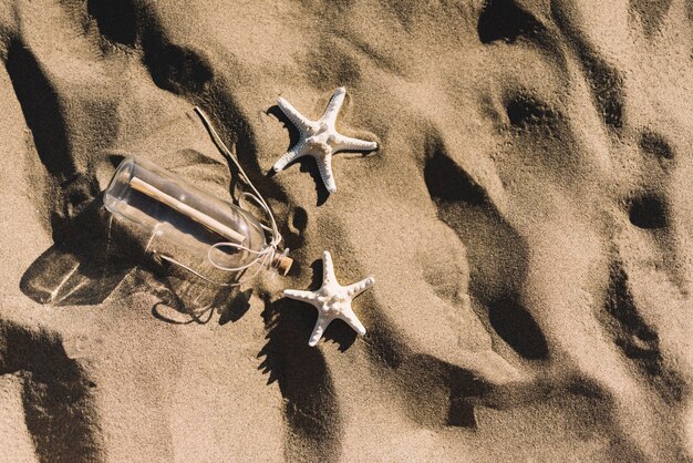 Бутылка и морские звезды на песке