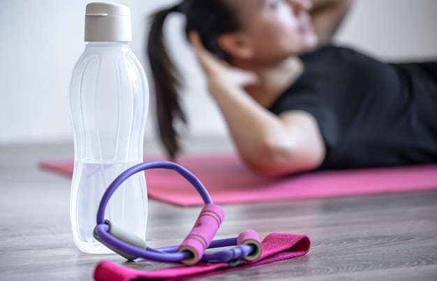 Bottle of water and an elastic band for fitness on a blurred background.
