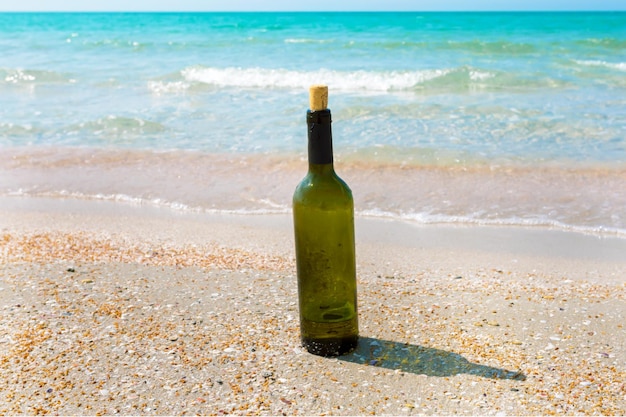 Free photo bottle of wine in sand on the beach