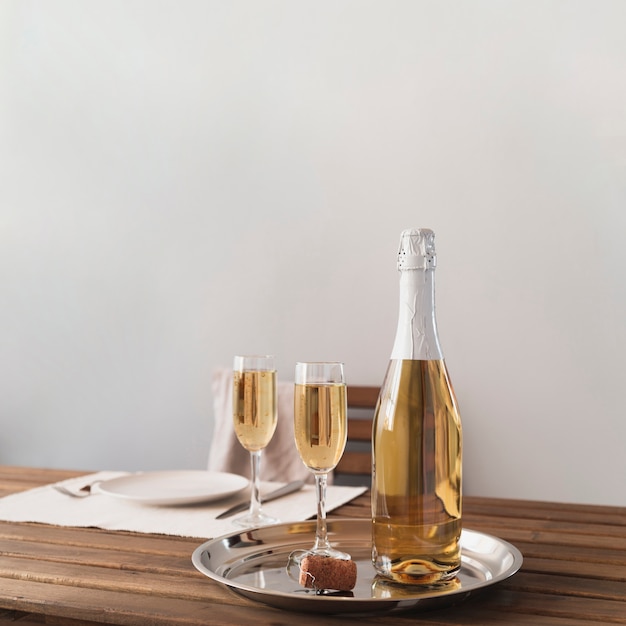 Bottle with champagne glasses on a tray