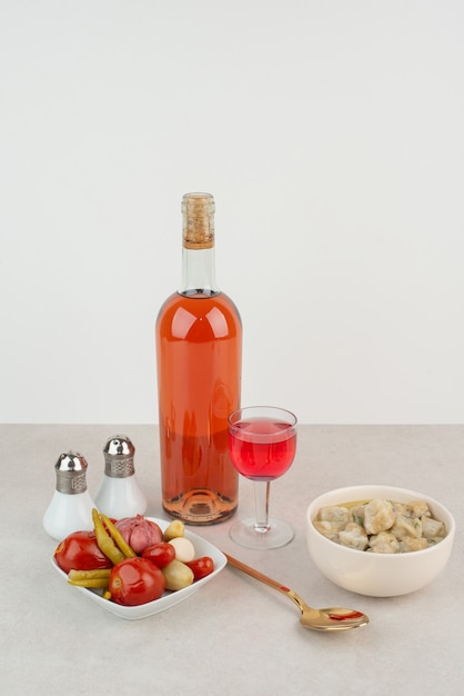 Bottle with glass of lemonade and plate of dumplings .