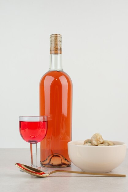 Bottle with glass of lemonade and plate of dumplings .