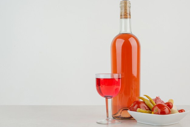 Bottle with glass of lemonade and plate of dumplings .