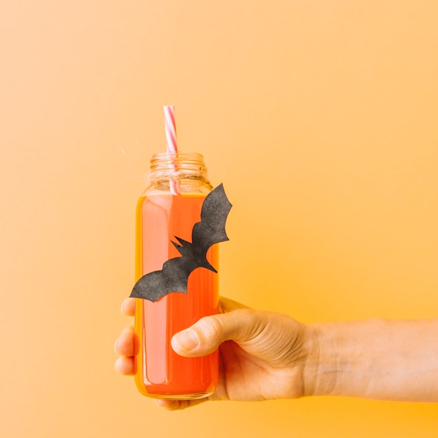 Free photo bottle with pumpkin drink and glued black bat