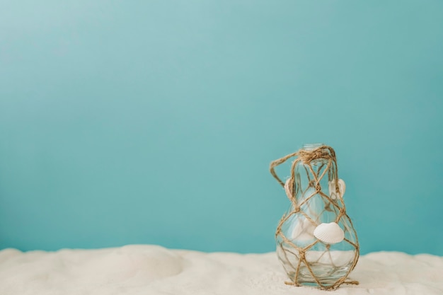 Free photo bottle with rope on sand