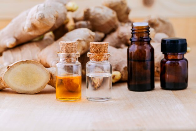 Bouteilles d'huile de gingembre et de gingembre sur fond de bois. Photo ...