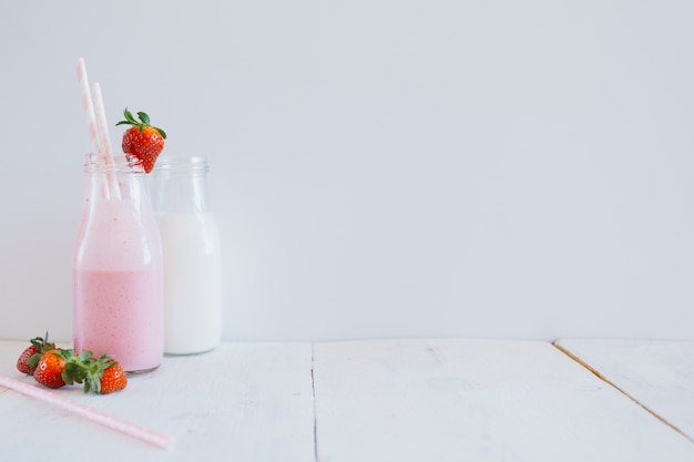 Bottles near strawberries on white background