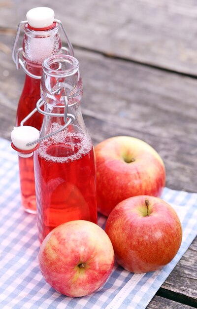 Бутылки с красными напитками и яблоками