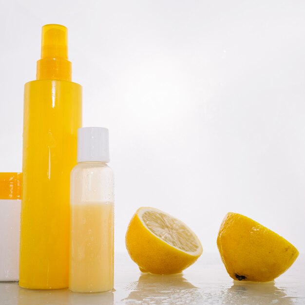 Бутылки с продуктами для ухода за кожей около лимона