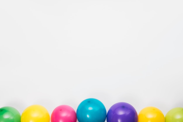 Foto gratuita bordo inferiore realizzato con palloncini colorati su sfondo bianco