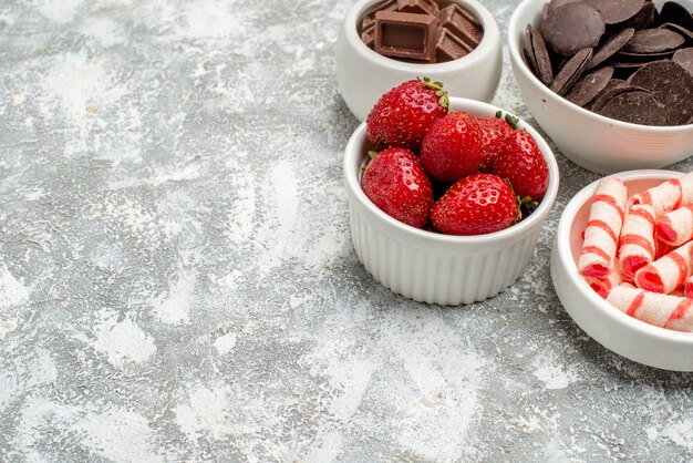 회색-흰색 배경의 오른쪽 상단에 딸기 사탕과 초콜릿이있는 하단 닫기보기 그릇