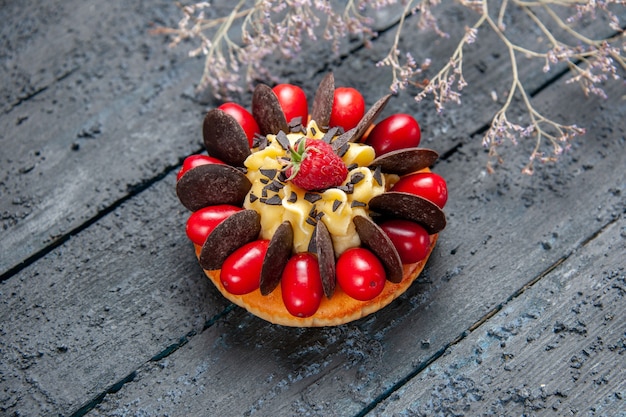 Торт снизу крупным планом с кизилом, малиной и шоколадом на темном деревянном фоне