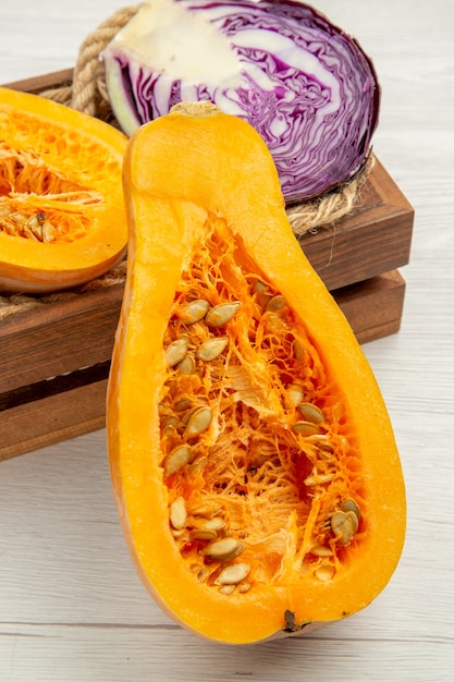 Bottom close view cut butternut squash cut red cabbage in wooden box on white table