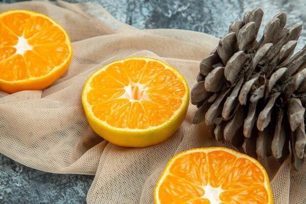 Вид снизу крупным планом нарезанные апельсины шишки на бежевой шали на темной поверхности