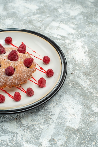 Free photo bottom half view berry cake on white oval plate on grey surface