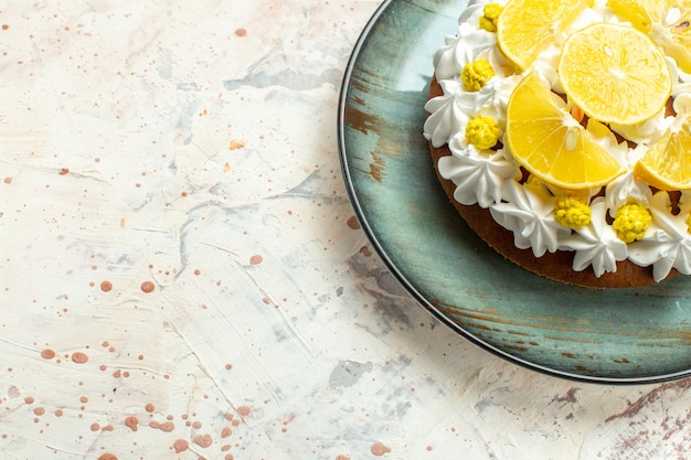 Torta a metà vista inferiore con crema pasticcera bianca e fette di limone su piatto rotondo su tavolo grigio chiaro