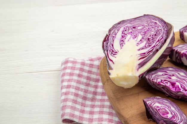 Bottom half view chopped red cabbage on cutting board on pink and white checkered kitchen towel on grey table free space