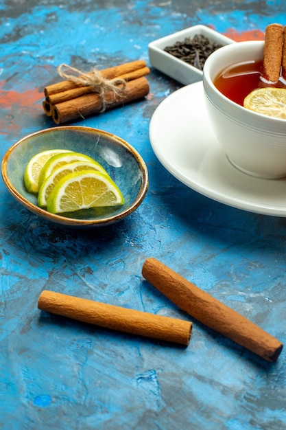 Bottom half view a cup of tea lemon slices cinnamon on blue red surface