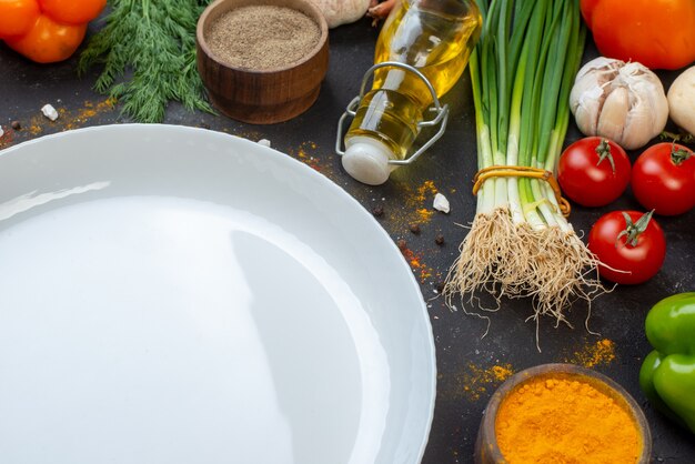 Bottom half view round plate black pepper powder in small bowl tomatoes oil bottle turmeric in small bowl on table