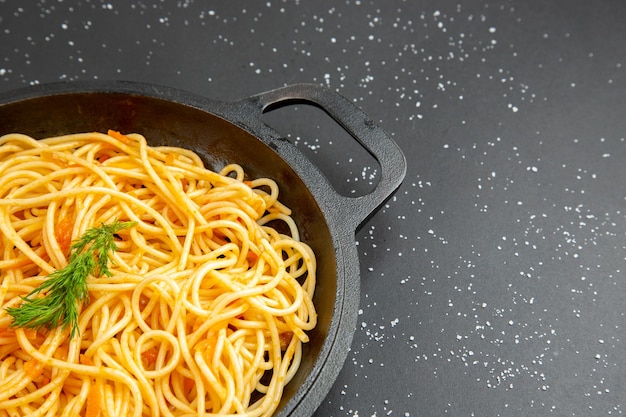 Bottom half view spaghetti frying pan on dark background