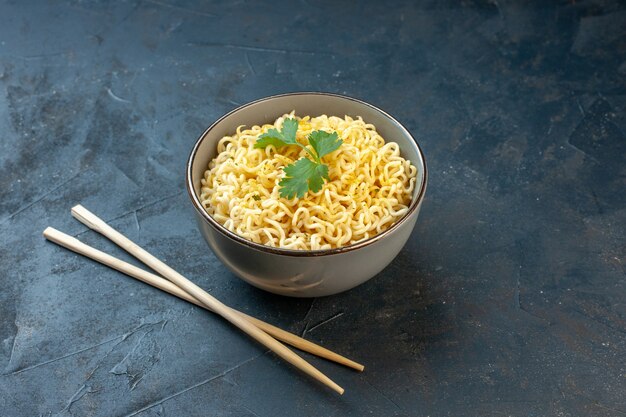 Bottom view asian ramen noodles with coriander in bowl chopsticks on dark table