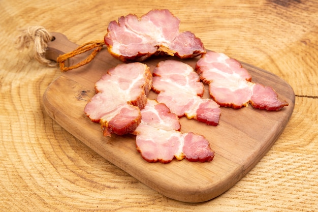 Bottom view becon slices on chopping board on wooden surface