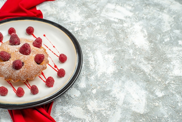 Bottom view berry cake on white oval plate red shawl on grey surface free space