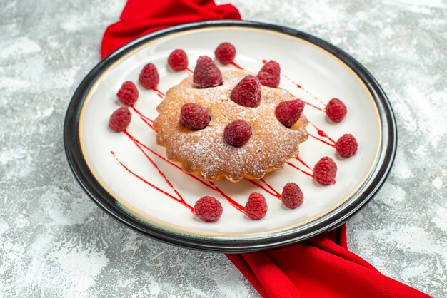 Bottom view berry cake on white oval plate red shawl on grey surface