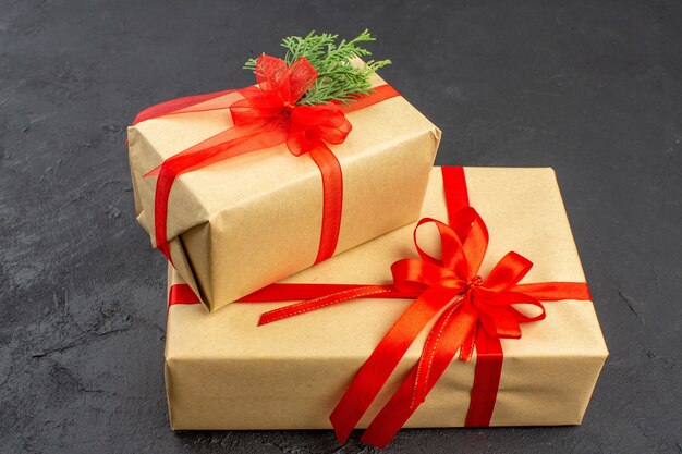 Bottom view big and small xmas gifts in brown paper tied with red ribbon on dark